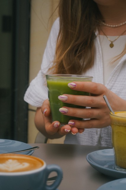 Hände halten ein Glas Matcha